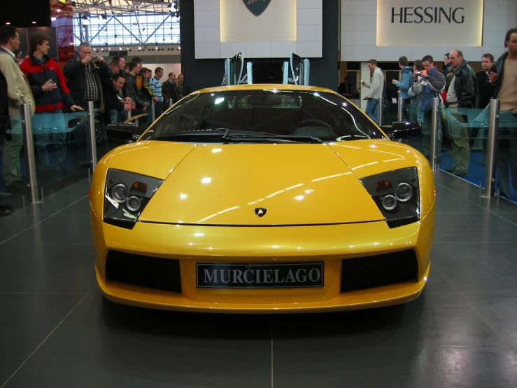 a yellow sports car parked in front of a crowd