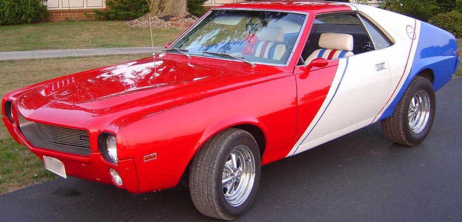 a red and white muscle car on driveway near grass