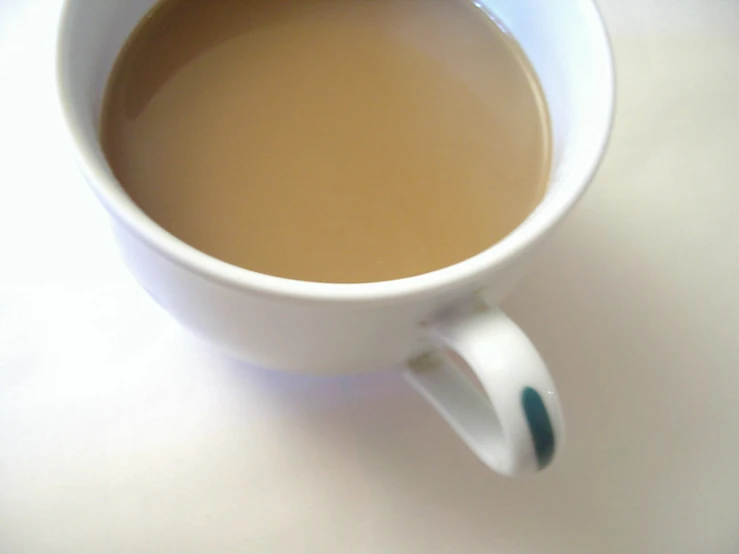 a white mug filled with tea sits on a counter