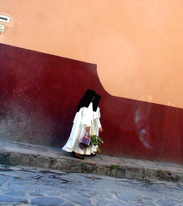 a woman in white with flowers walking down the street