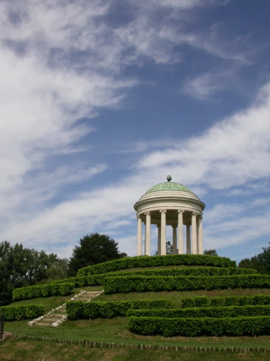 a building sits atop a grass hill with shrubs