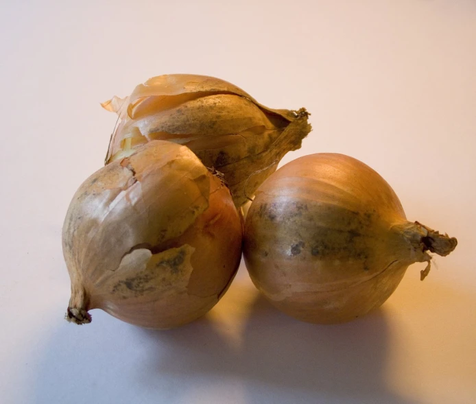 three onions on a table next to one another