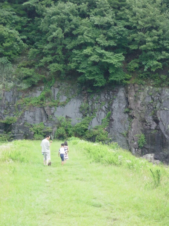 two people walking down a path by a rock face