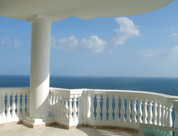 a balcony overlooking the ocean has columns to serve as an umbrella