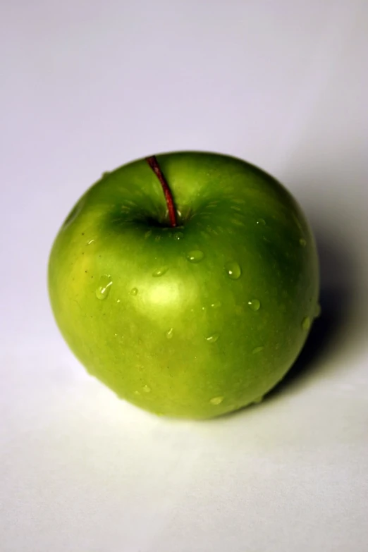 a green apple sitting in the center of a table