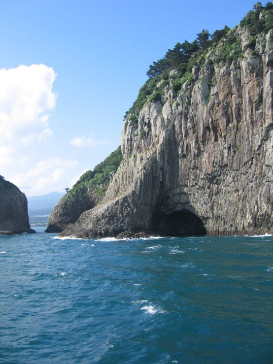 a cliff sticking out from a lake next to another mountain