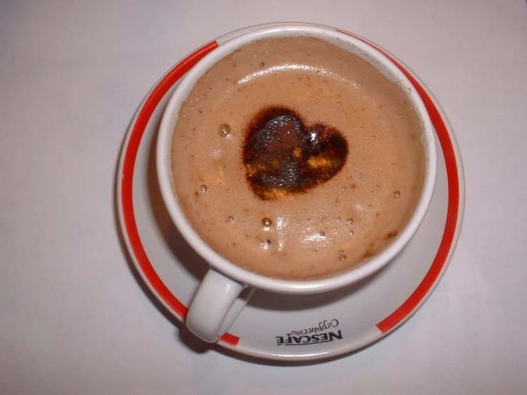 white cup with saucer and red border around the edge