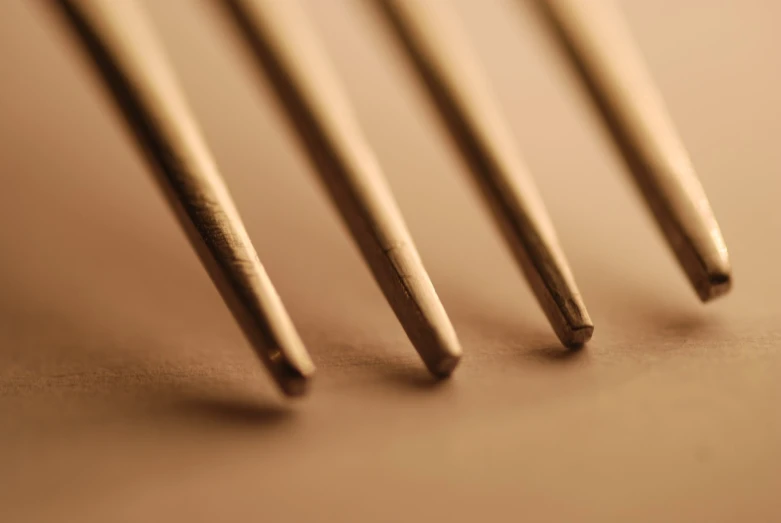 four gold - colored stick sticks are seen stacked up