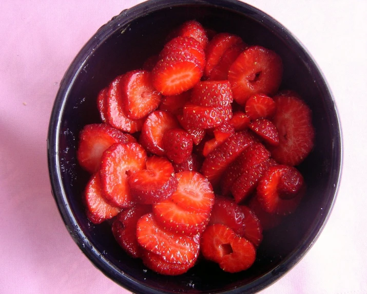 a bowl filled with strawberries on top of a white table