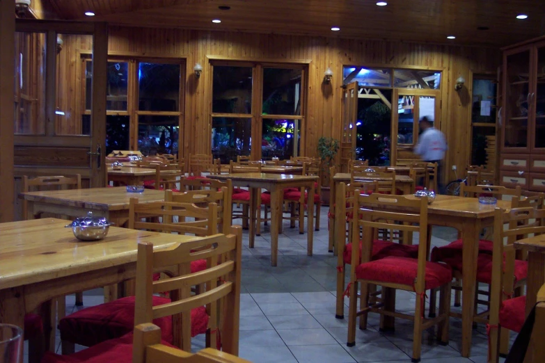 a restaurant has red chairs and large wooden tables