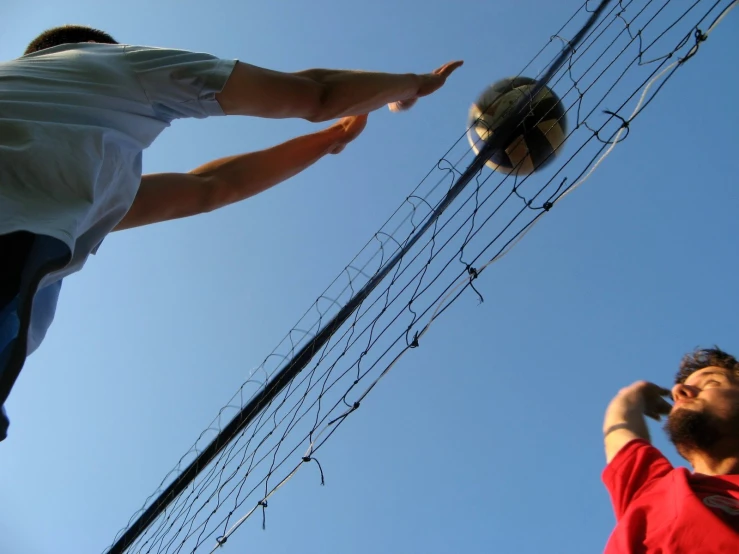 two men stand near some wire holding a ball