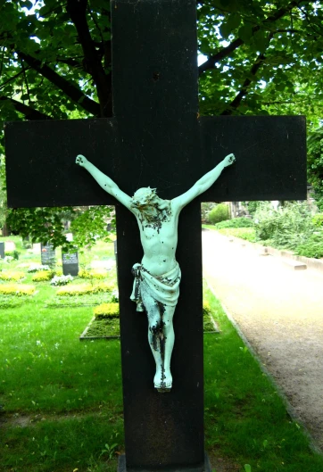 a statue on top of a cross in the grass