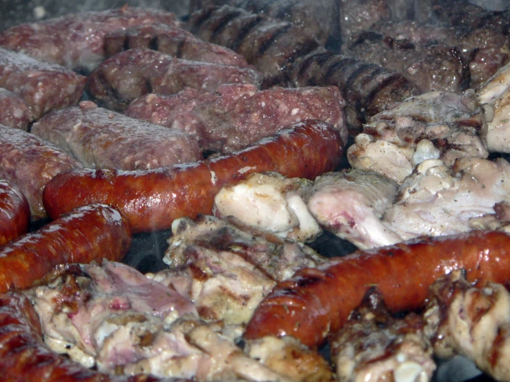food being cooked on a grill with some meat and meatballs