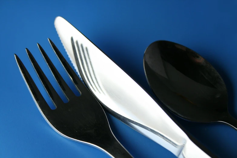 a close up of two black forks and a white spoon