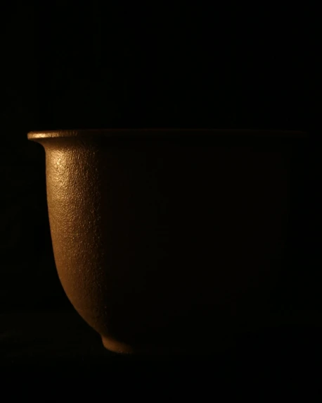 a brown ceramic bowl in the dark on the table