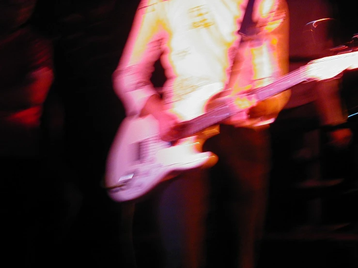 blurry image of guitar player with white and orange bass