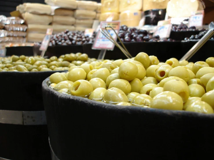 olives in a barrel with spoons are being sold