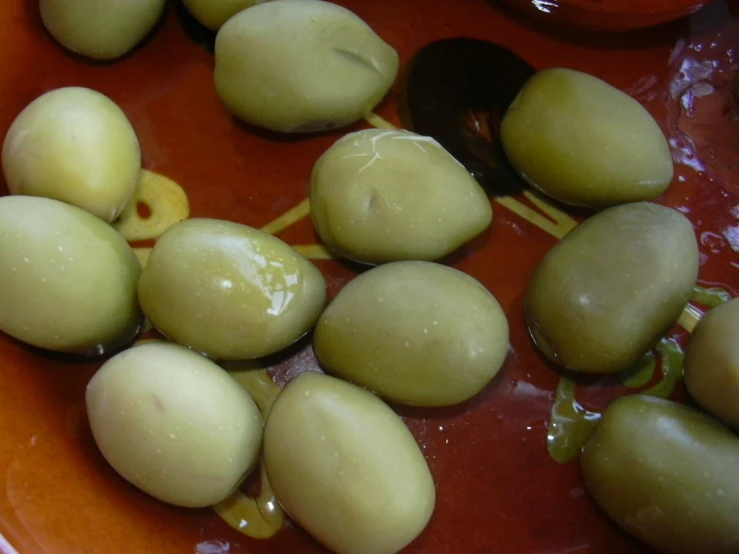 several olives being cut in half with a large spoon