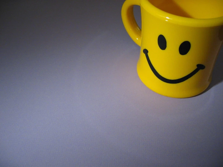 a yellow mug has a smiley face drawn on it