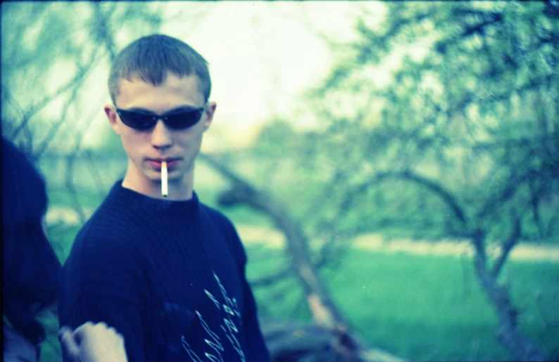 a man with a cigarette in his mouth standing outside