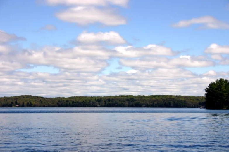 the sky is filled with clouds as a boat sails on the water