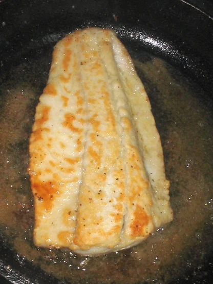 a pan frying chicken covered with cheese
