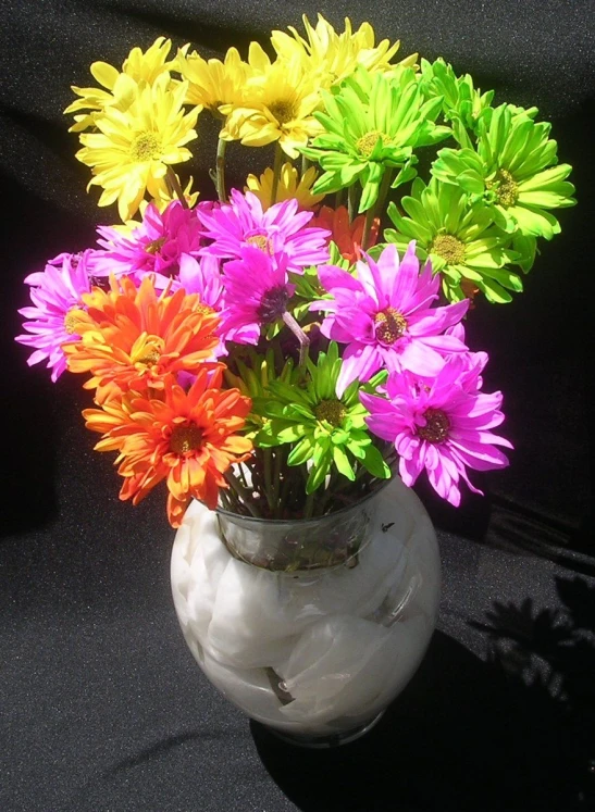 a white vase with a bunch of different colored flowers