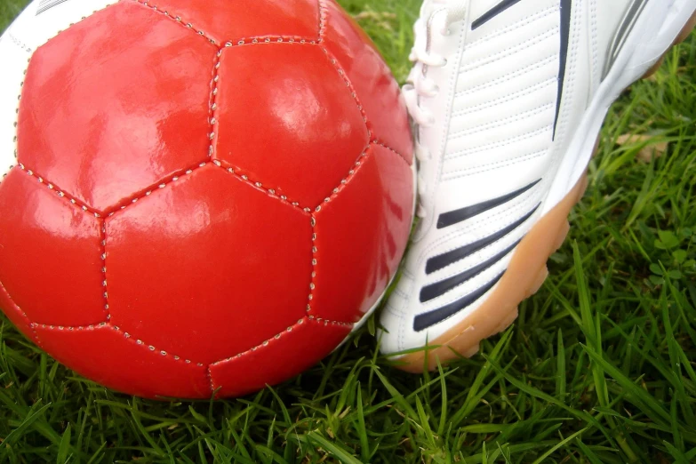 a close up of two red soccer balls on the grass