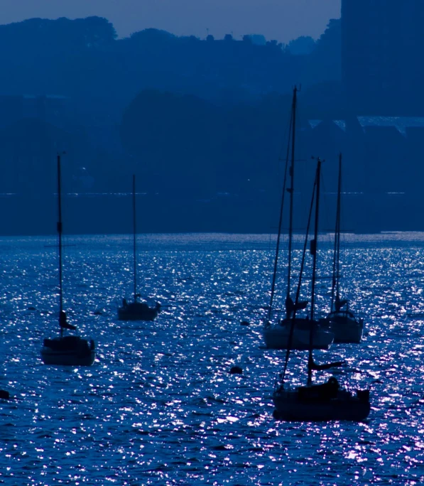 several sailboats floating on the ocean at night