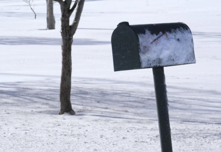 a mailbox on the side of the road covered in snow