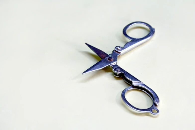 a pair of scissors laying on top of a white table