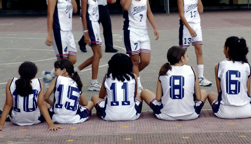 the girls basketball team are sitting in a huddle