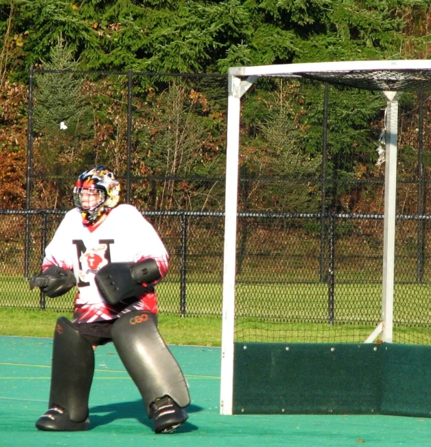 a woman in white shirt sitting on the field with a goalie outfit