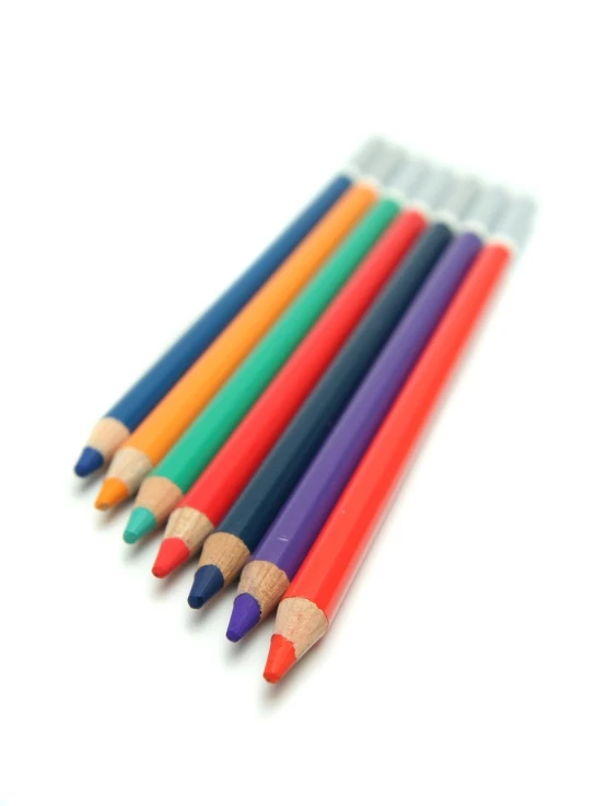 five different colored pencils on a white table