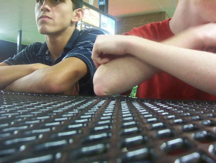 two men sit at a computer desk in a store