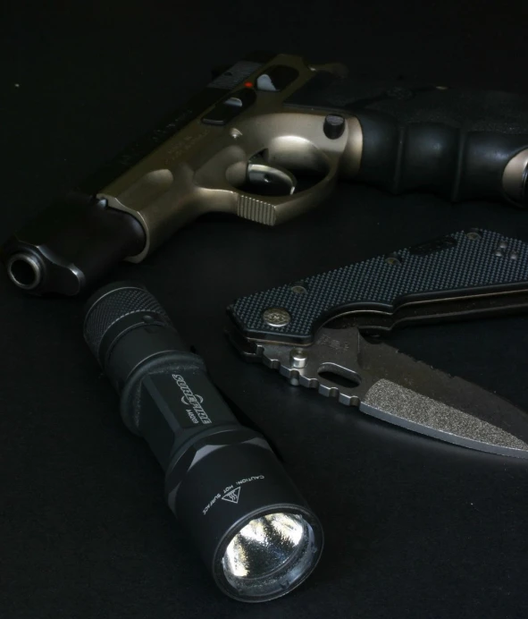an flashlight, knife and light on a black background