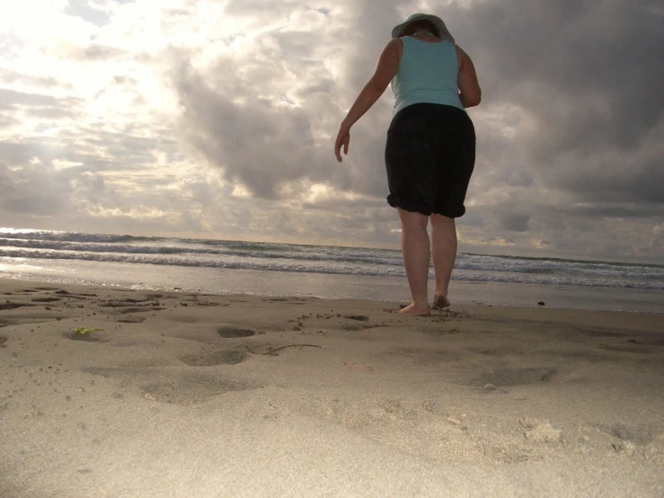 a girl walking on the beach with a kite