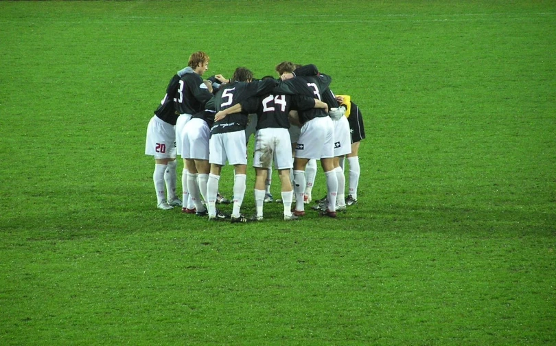 a group of young people huddle together on the field