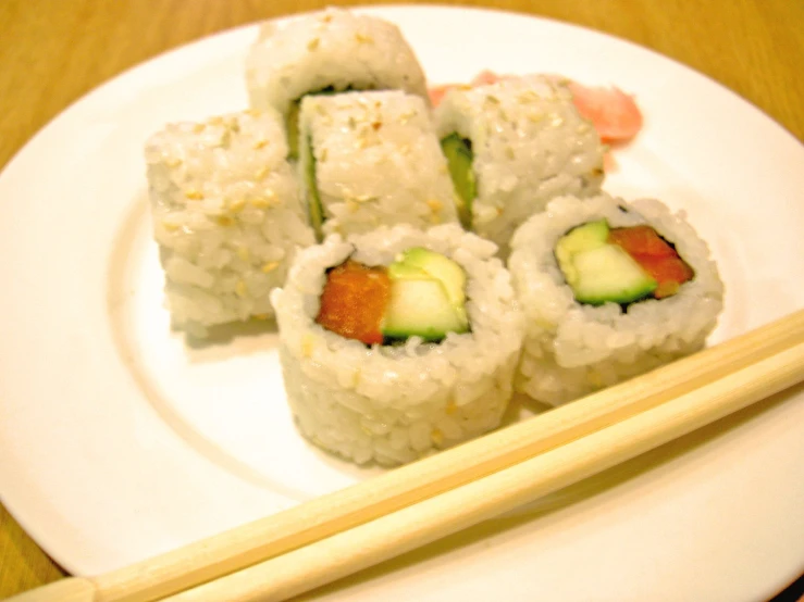 several pieces of sushi with chop sticks on the plate