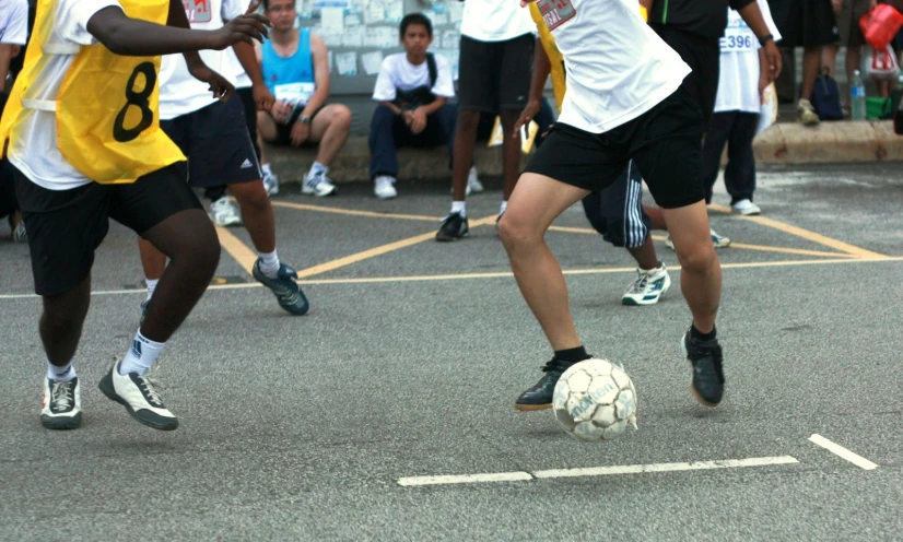 boys in shorts and shirts running towards the soccer ball