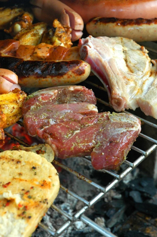 some meats, sausage and other food are cooking on a grill