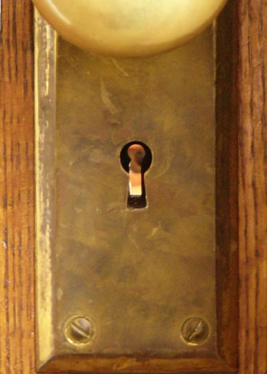 a wooden clock with a keyhole mounted on it