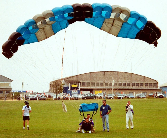 a couple people that are parasailing in the grass