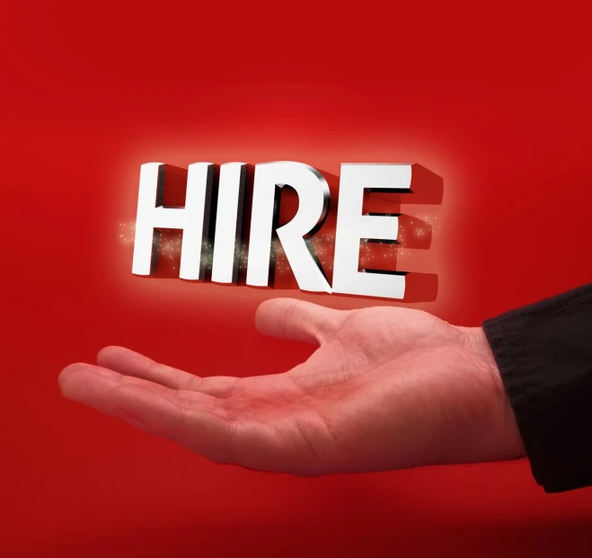 a hand holding up a piece of paper that says hire