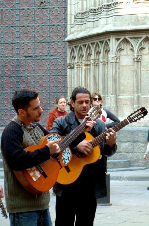 two men are playing the ukulele as others watch