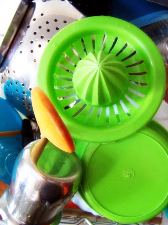 a green metal grater sitting on top of a pile of cooking utensils