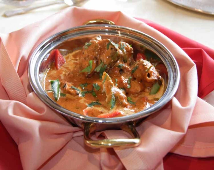 a dish of meat and vegetables served on an elegant silver plate