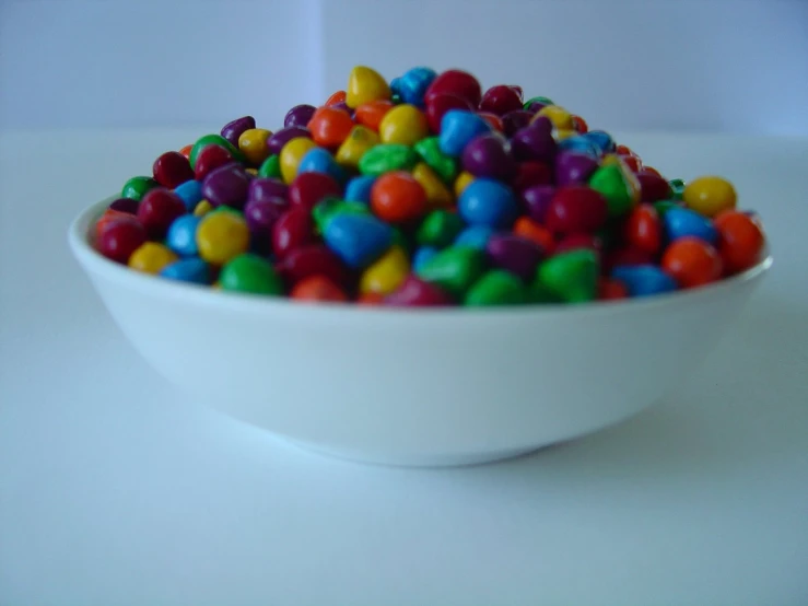 a bowl filled with colorful candy sitting on a table