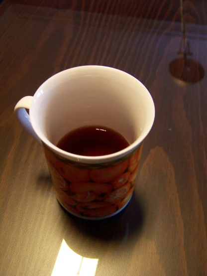 a mug with some coffee sitting on a wooden table