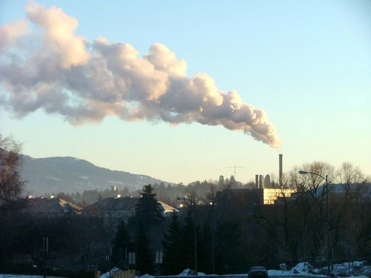 a factory with smoke pouring from its pipe